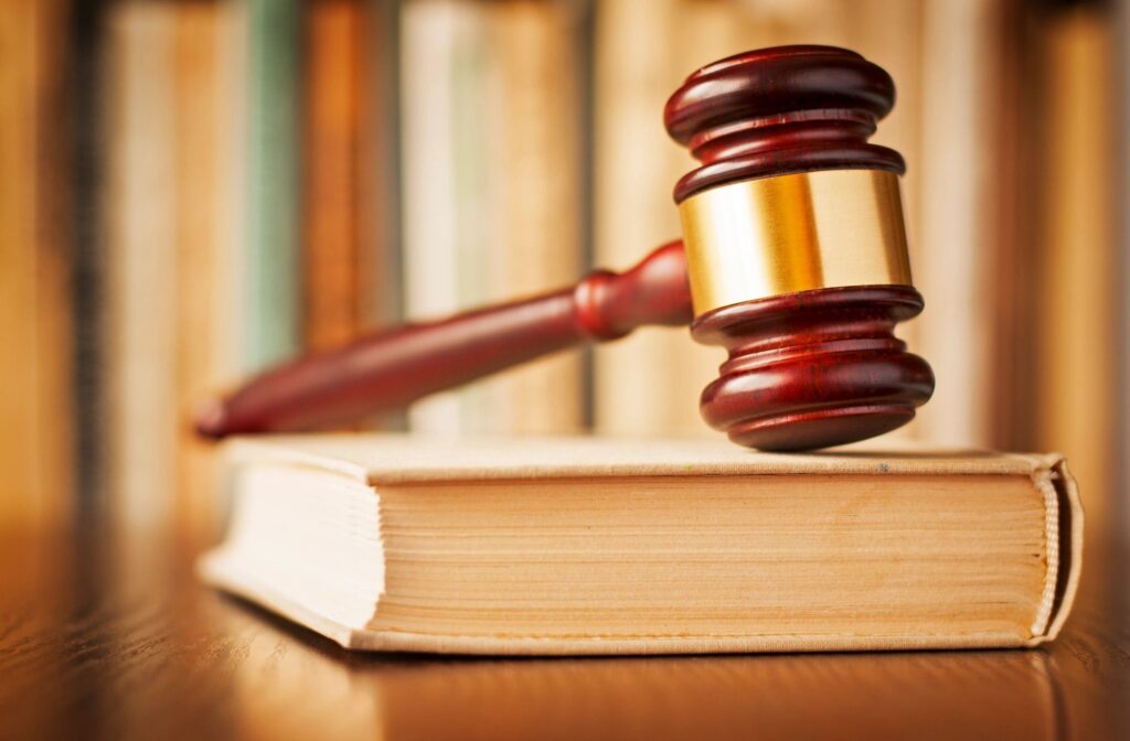 Gavel on law book near bookshelves.